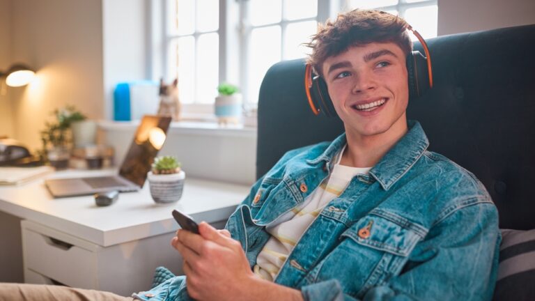 teenage boy in his room with headphones on listening to music